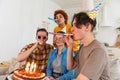 Make a wish. Woman wearing party cap blowing out burning candles on birthday cake. Happy Birthday party. Group of Royalty Free Stock Photo
