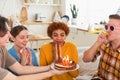 Make a wish. Woman wearing party cap blowing out burning candles on birthday cake. Happy Birthday party. Group of Royalty Free Stock Photo