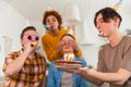 Make a wish. Woman wearing party cap blowing out burning candles on birthday cake. Happy Birthday party. Group of Royalty Free Stock Photo