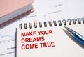 MAKE YOUR DREAMS COME TRUE text written on notepad with pen on financial documents Royalty Free Stock Photo
