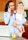 She makes balancing work and home look easy. a happy-looking single mom talking on the phone while cradling her baby. Royalty Free Stock Photo