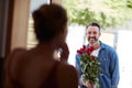 He always makes her Valentines special. an attractive mature man surprising his girlfriend with a bouquet of roses.