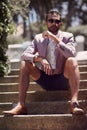 He makes it kinda hard not to stare. a well-dressed young man sitting outside on a staircase.