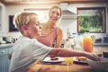 It makes me happy when he eats like this. a woman sitting with her son while hes having breakfast.