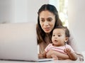 She makes working from home with a baby look easy. a woman working on her laptop while sitting with her baby on her lap. Royalty Free Stock Photo