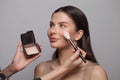 Makeup artist applies blush make-up to a healthy skin of cute female model woman Royalty Free Stock Photo