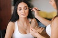 Makeup artist applies eye shadow, perfect evening makeup. Beauty brunette girl with perfect skin in studio Royalty Free Stock Photo