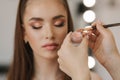 Makeup artist applies eye shadow, perfect evening makeup. Beauty redhead girl with perfect skin and freckles Royalty Free Stock Photo