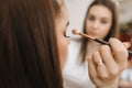 Makeup artist applies eye shadow, perfect evening makeup. Beauty redhead girl with perfect skin and freckles Royalty Free Stock Photo