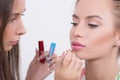 Makeup artist applies lipstick. Beautiful woman