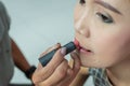 Makeup artist applies red lipstick . Beautiful woman face. Hand of make-up master, painting lips of young beauty asian model girl Royalty Free Stock Photo