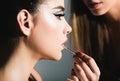 Makeup artist applies red lipstick. Hand of make up master, painting lips of young beauty model girl. Skincare facial Royalty Free Stock Photo