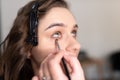 Makeup artist applying eye shadow to the lower eyelid of a girl with a brush Royalty Free Stock Photo