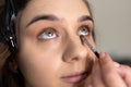 Makeup artist applying eye shadow to the lower eyelid of a girl with a brush Royalty Free Stock Photo