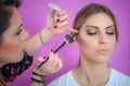 Makeup artist applying makeup on her face using powder brush Royalty Free Stock Photo