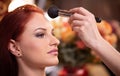 Makeup artist applying liquid tonal foundation on the face of the woman in white make up room. Beauty and fashion Royalty Free Stock Photo