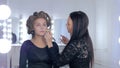 Makeup artist applying liquid tonal foundation on woman`s face Royalty Free Stock Photo