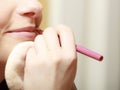 Makeup artist applying with pencil cosmetic on lips of woman