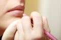 Makeup artist applying with pencil cosmetic on lips of woman