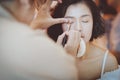 Makeup artist applying pink eyeshadow to beautiful Asian model Royalty Free Stock Photo