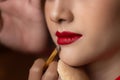 Makeup artist applying red lipstick on beautiful model mouth by using lip brush. Attractive beautiful woman has beautiful plump Royalty Free Stock Photo