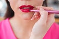 Makeup artist applying red lipstick to lips of woman Royalty Free Stock Photo