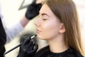 Makeup artist applying the tone of the foundation using special brush on face young beautiful model Royalty Free Stock Photo