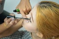 Makeup artist asian woman applying cosmetic mascara on eyelashes using curling brush Royalty Free Stock Photo
