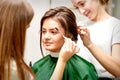 Makeup artist combing eyebrows and hairstylist preparing hairstyle