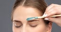 Makeup artist does facial hair removal procedure. Beautiful girl with blue eyes having Permanent Make-up on her Eyebrows. Royalty Free Stock Photo