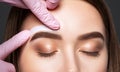 Makeup artist does facial hair removal procedure. Beautiful girl having Permanent Make-up on her Eyebrows. The make-up artist does Royalty Free Stock Photo