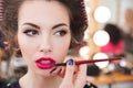 Makeup artist doing makeup and applying pink lipstick using brush Royalty Free Stock Photo