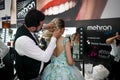 Makeup artist and hairstylist applying professional makeup on a young blond woman in a colorful dress