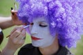 Makeup artist making clown face painting to the actor