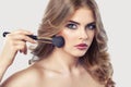 The Makeup artist paints powder on the girl`s face, completes make-up in the beauty salon. Royalty Free Stock Photo