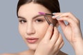 Makeup artist plucks eyebrows with tweezers to a woman before staining with henna. Women`s cosmetology in the beauty salon