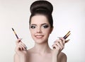 Makeup artist. Pretty teen girl with cute bun hairstyle and fashion beauty makeup, brunette holding brushes in hand isolated on w