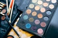 Makeup artist set. Close-up of a palette of eyeshadows of different colors and brushes for applying makeup on a blurred