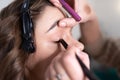 The makeup artist sets the shade with a cosmetic pencil on the upper eyelid