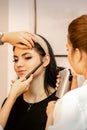 Makeup artist using an airbrush on the face of a young caucasian woman in a beauty salon.