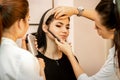 Makeup artist using an airbrush on the face of a young caucasian woman in a beauty salon.