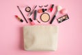 Makeup bag with cosmetic products spilling out on to pastel pink background. Flat lay, top view. Glamour make up artist pouch with Royalty Free Stock Photo