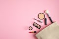 Makeup bag with cosmetic products spilling out on to pastel pink background. Flat lay, top view. Stylish make up artist pouch with Royalty Free Stock Photo