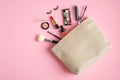 Makeup bag with cosmetic products spilling out on to pastel pink background. Flat lay, view from above. Stylish make up artist Royalty Free Stock Photo