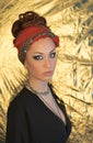Makeup. Beautiful woman, elegant lady, original style, gold background. Brunette with red headband