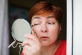 Makeup beauty care woman. Adult woman looks into mirror and putting eye pencil color on eyes