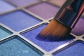 Makeup brush on blue shadows. Bright shadows for the summer. Macro frame of shadows. Bright cosmetics, fashionable colors. Royalty Free Stock Photo