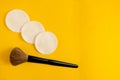 Makeup brush and clean sponges on yellow background with copy space. Instruments of fashion beautician or home cosmetics applying