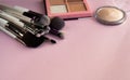 Makeup brush and cosmetics, on a pink background