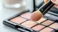 Makeup brush touching eyeshadow palette in soft tones. Beauty product, cosmetics Royalty Free Stock Photo